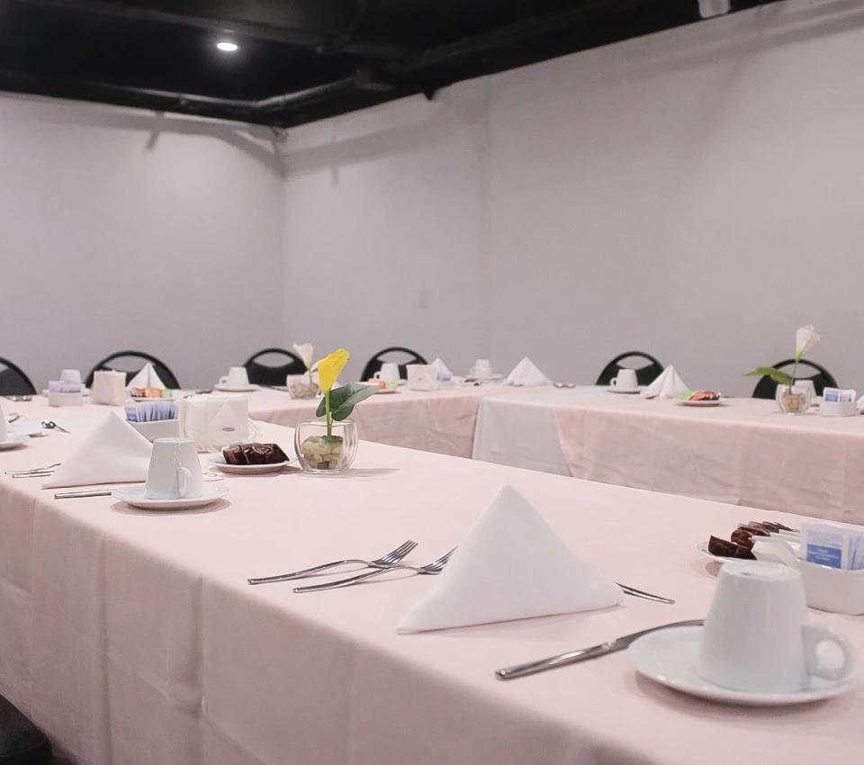 Mesa preparada para evento con manteles blancos y vajilla b&aacute;sica.
