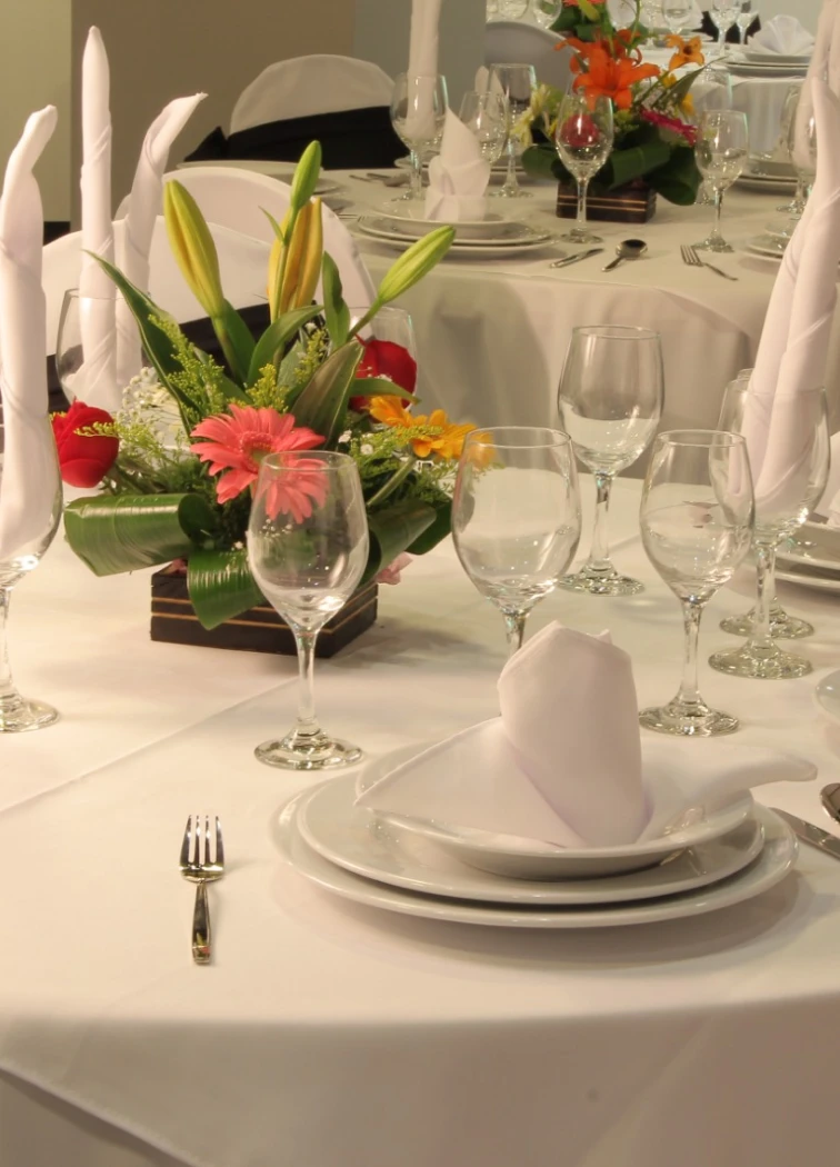 Mesa elegantemente decorada con copas y flores coloridas en el centro.