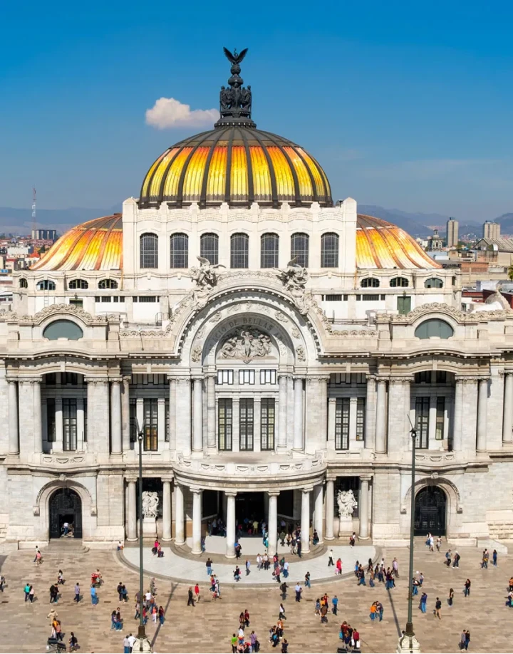 Edificio hist&oacute;rico con c&uacute;pula dorada y personas caminando enfrente.