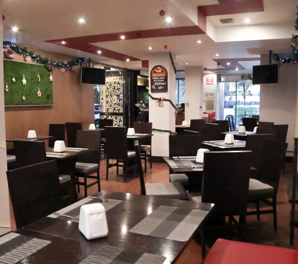 Restaurante vac&iacute;o con mesas y sillas, decorado para Navidad.