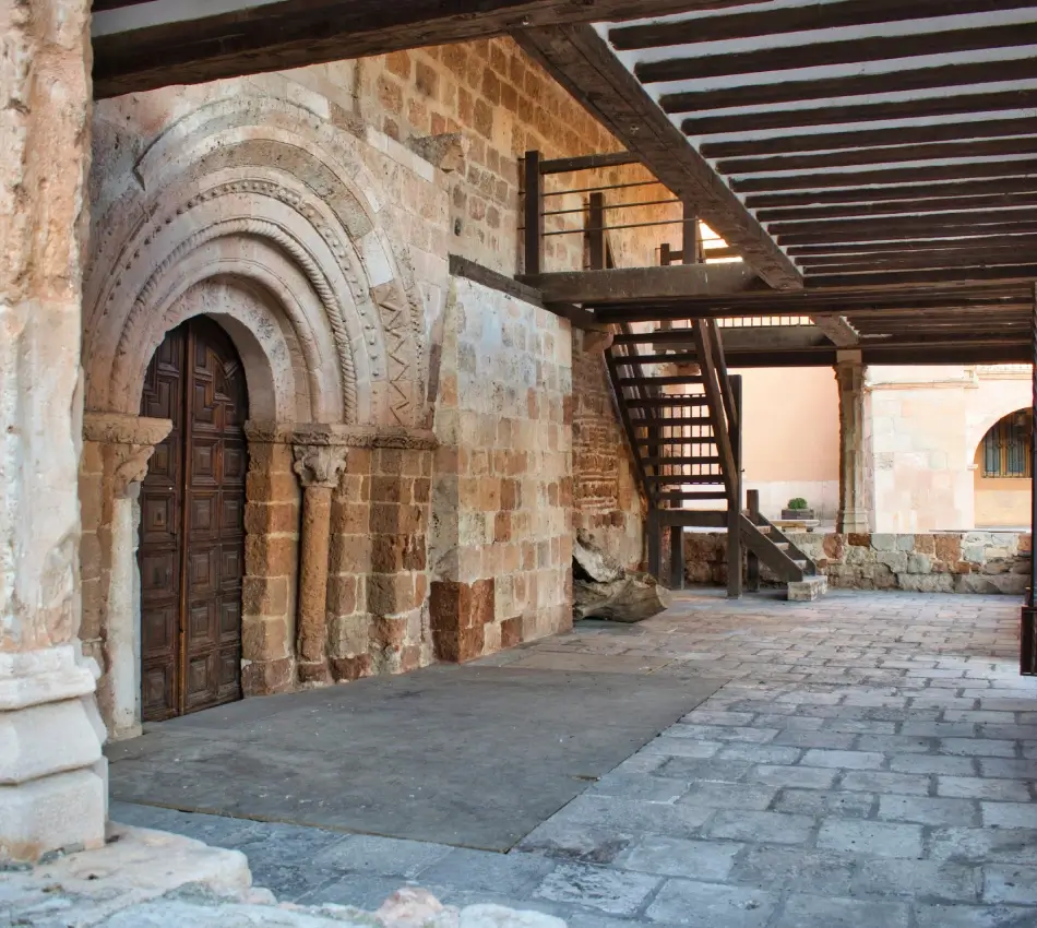 Puerta de arco y escaleras de madera en un edificio antiguo de piedra.