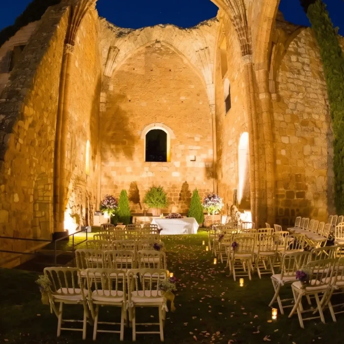 Ruinas iluminadas para una ceremonia al aire libre con sillas y altar.