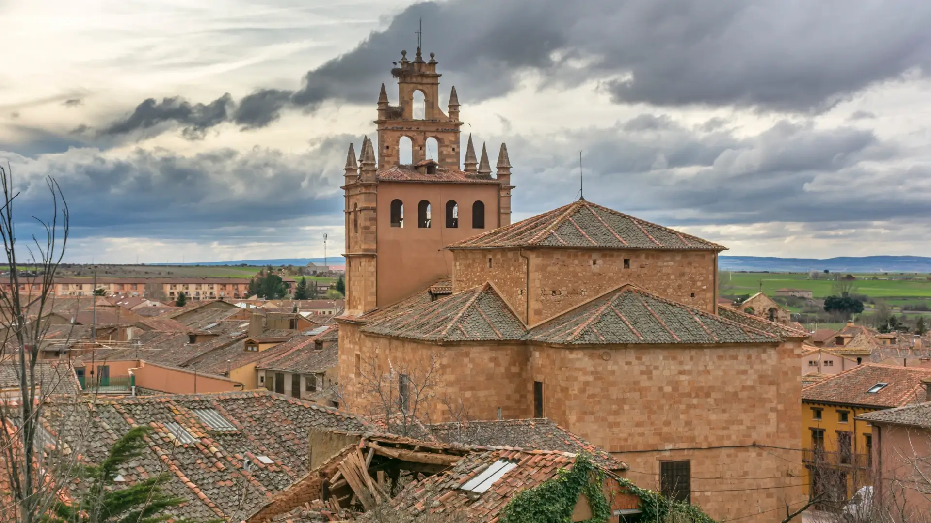Paisaje de casas de ladrillo y torre con cielo nublado en un pueblo rural.