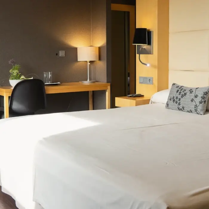 Habitaci&oacute;n con cama, escritorio, l&aacute;mparas y decoraci&oacute;n minimalista.
