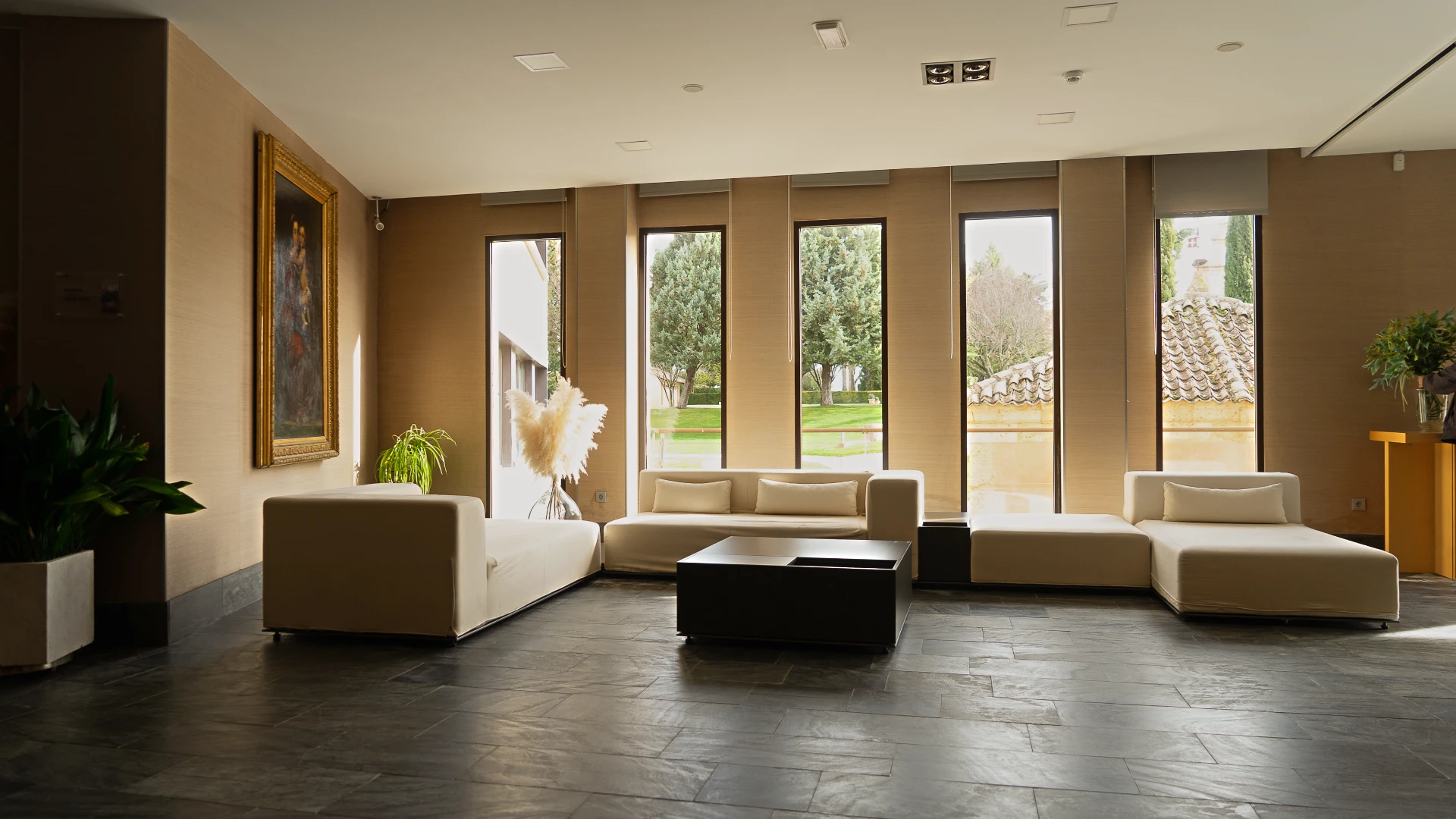 Sala moderna con sillones blancos y grandes ventanas al exterior.