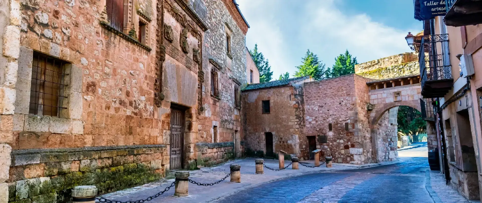 Calle empedrada con edificios de piedra y un arco antiguo.