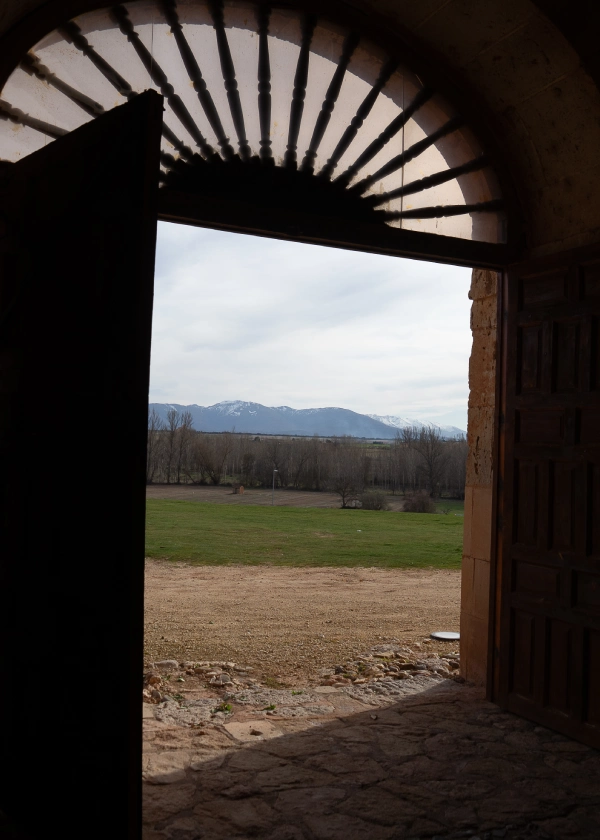 Vista de un campo y monta&ntilde;as desde la puerta de una iglesia.