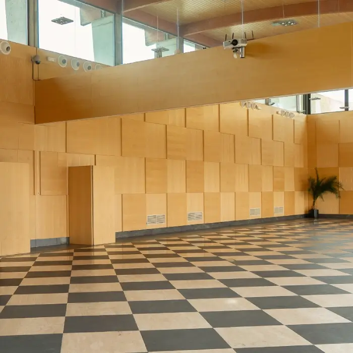 Sala vac&iacute;a con paredes de madera y suelo ajedrezado blanco y negro.