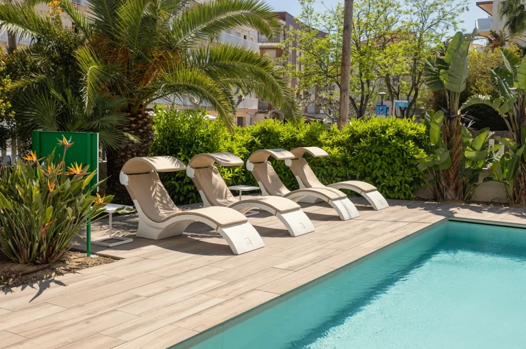 Piscina al aire libre con tumbonas y sillas modernas bajo pérgola de madera.