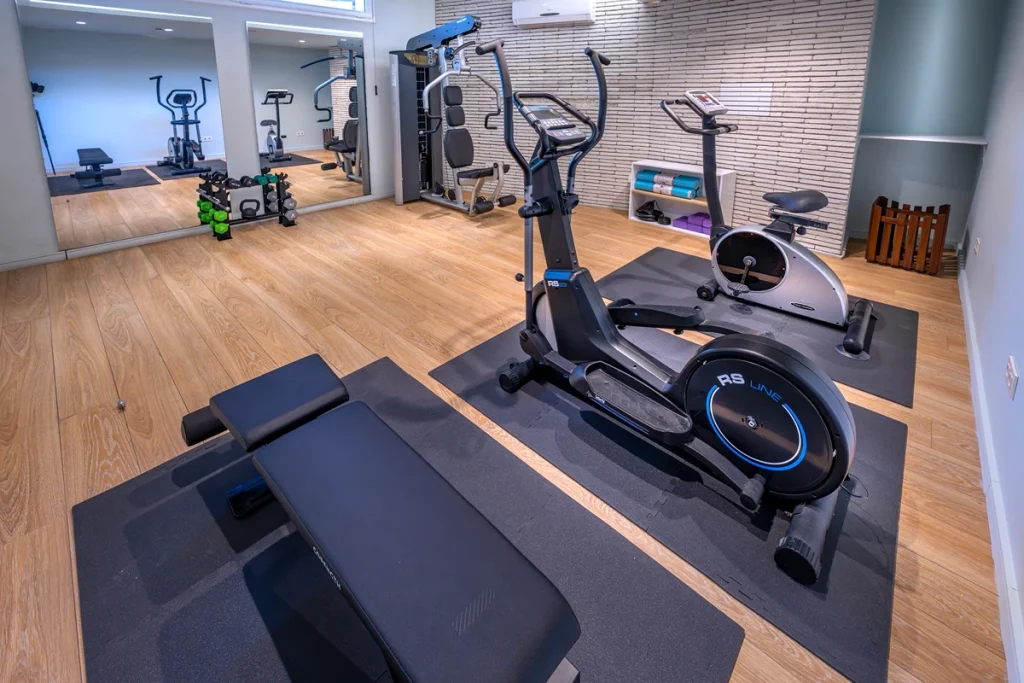 Gimnasio con m&aacute;quinas de ejercicio y espejos en un sal&oacute;n moderno.