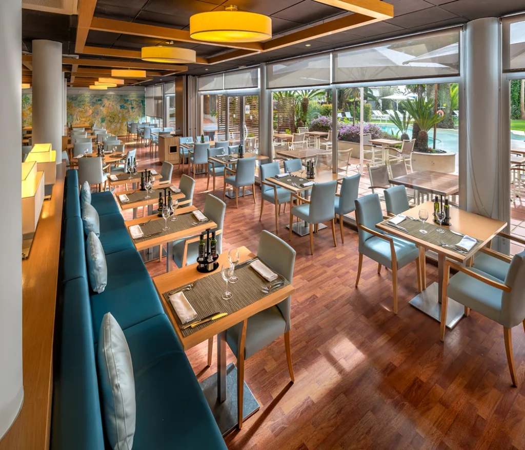 Restaurante elegante con mesas preparadas y luz natural abundante.