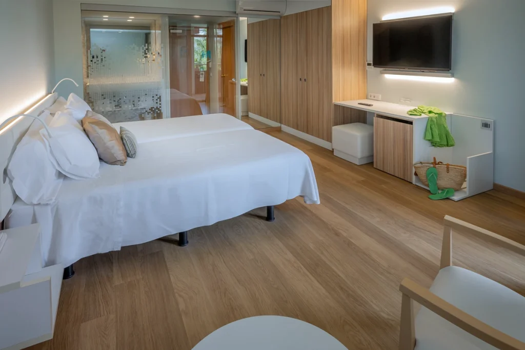 Habitaci&oacute;n moderna con cama, TV, escritorio y puf.