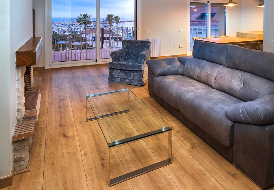 Sala moderna con sof&aacute;s grises, mesa de comedor y cocina integrada.