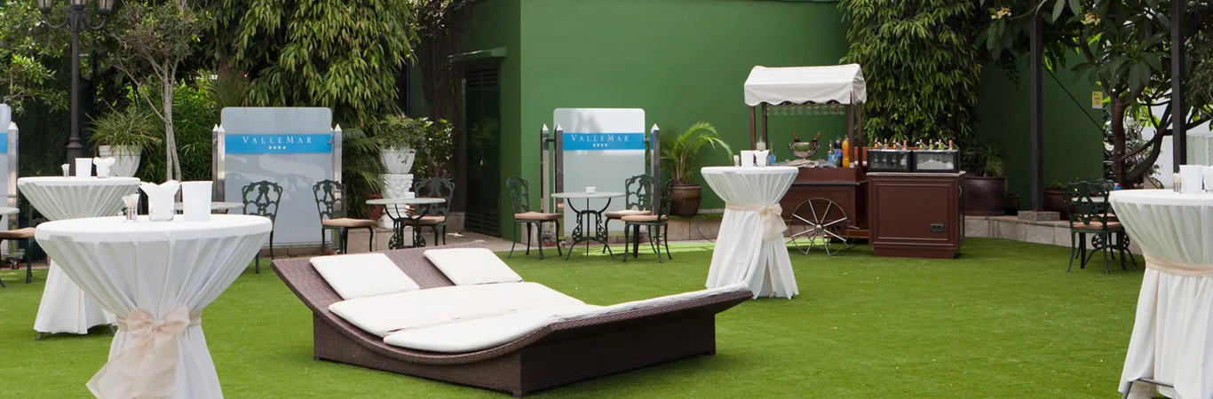Zona de banquete en jard&iacute;n con mesas, tumbonas y barra de bebidas al aire libre.