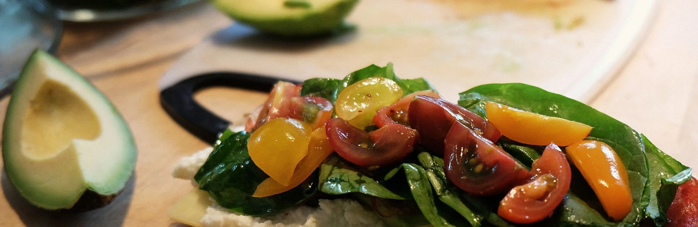 Ensalada con hojas verdes, tomates cherry, pepino y lim&oacute;n en primer plano