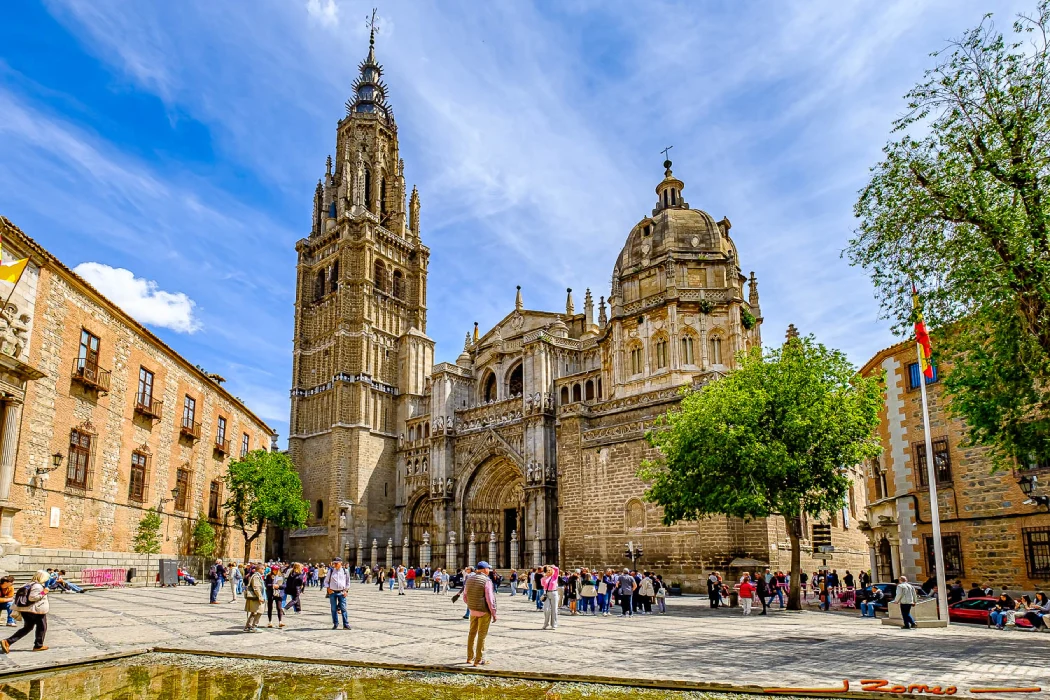 Catedral g&oacute;tica en una plaza concurrida bajo un cielo azul.