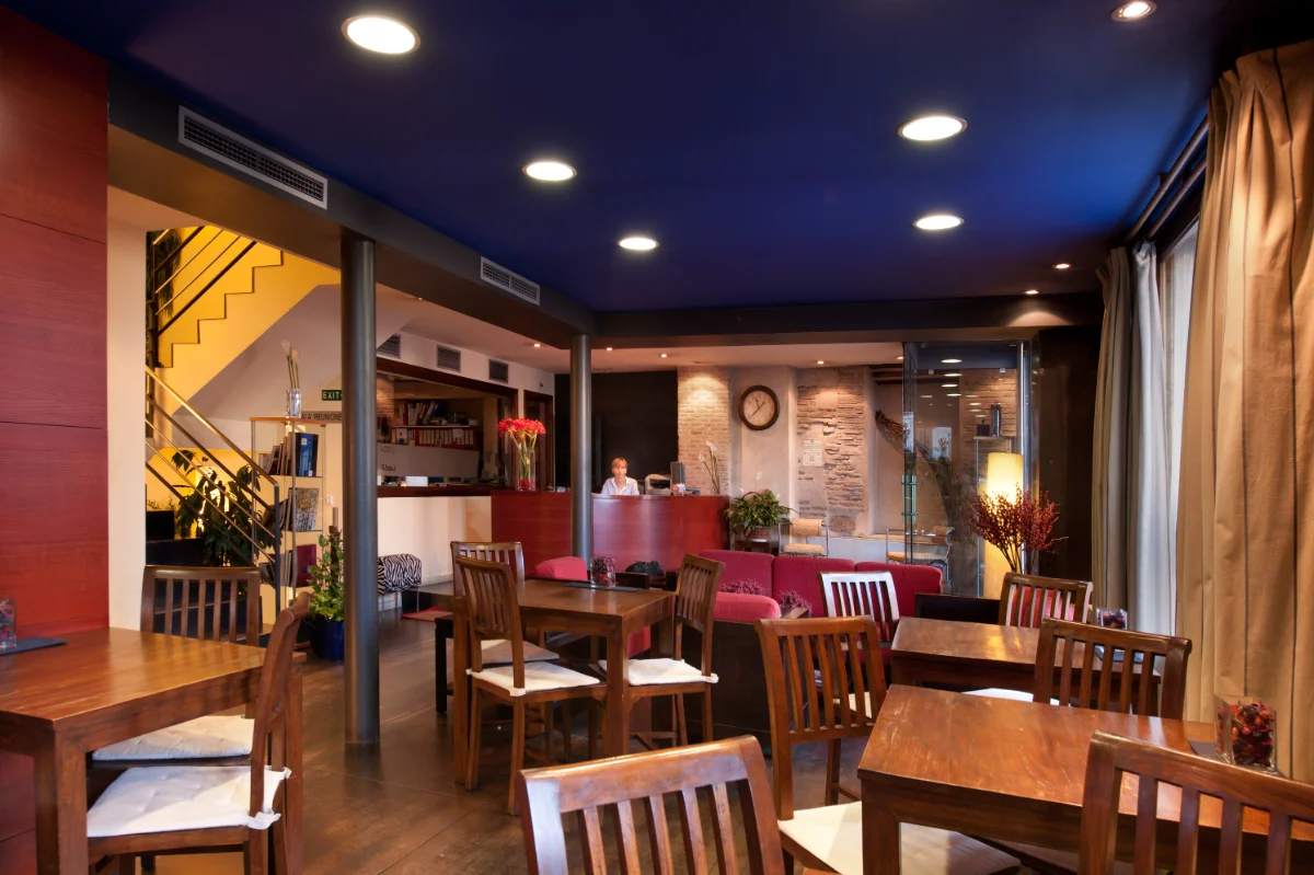 Recepci&oacute;n de hotel con mesas de madera y decoraci&oacute;n moderna.