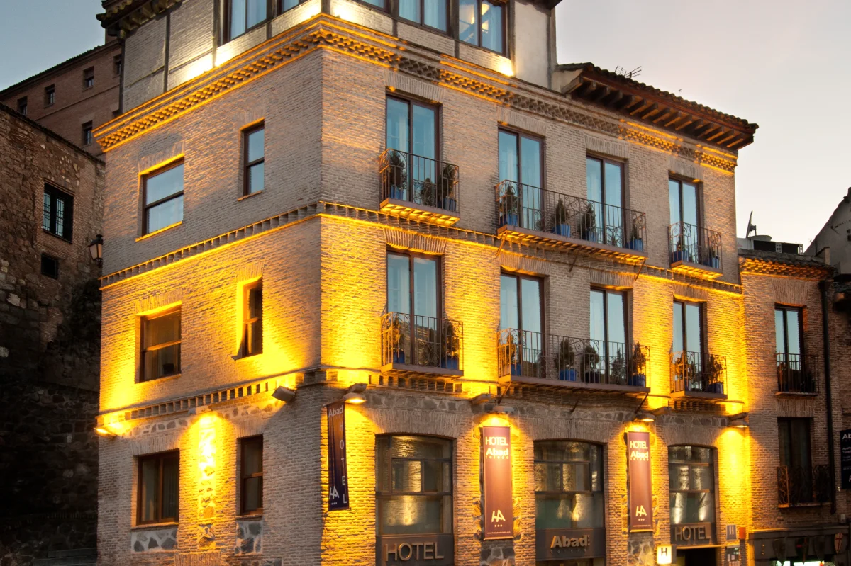 Edificio iluminado al atardecer con fachada de ladrillo y varios balcones.
