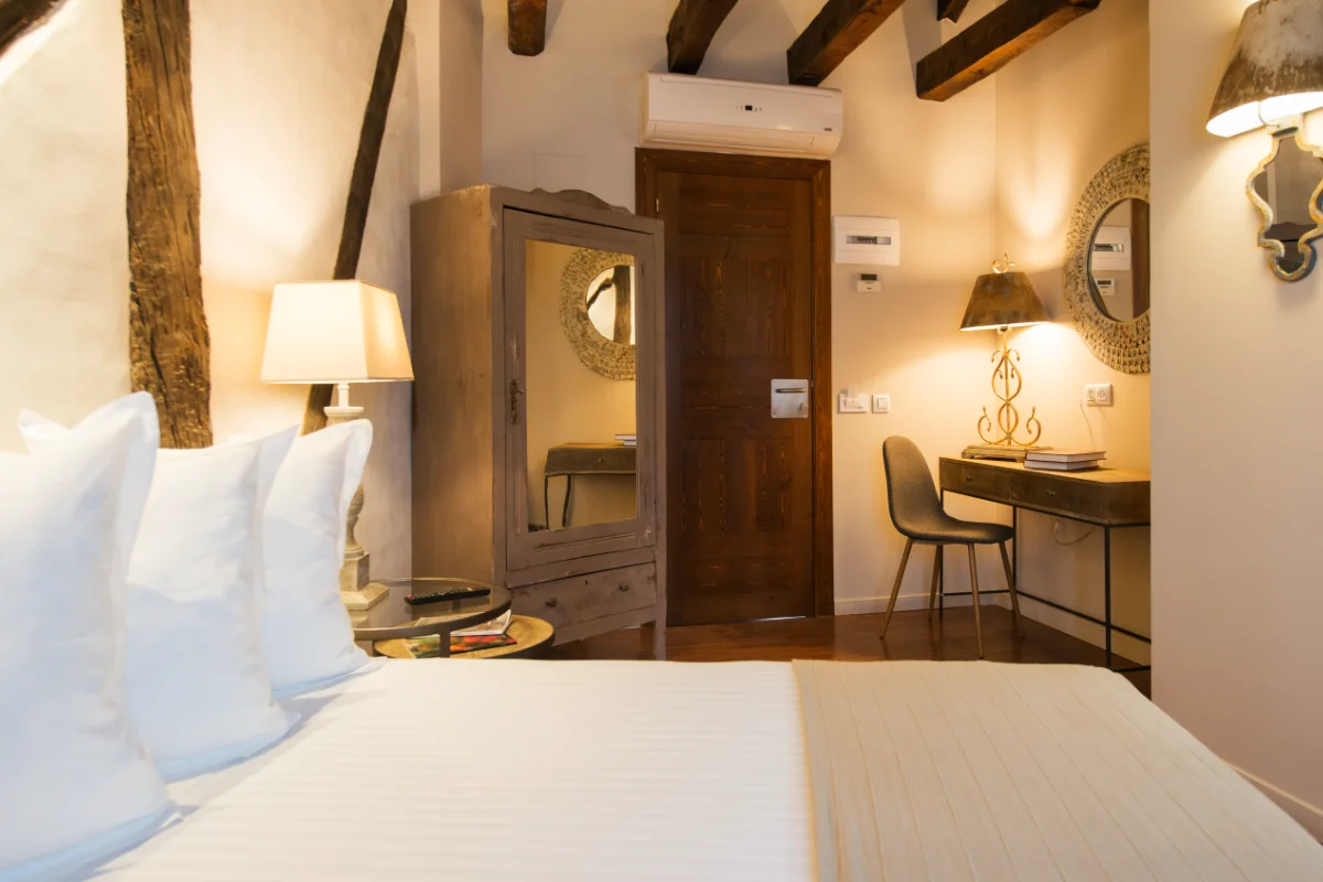 Habitación acogedora con cama, armario y escritorio iluminados por lámparas.