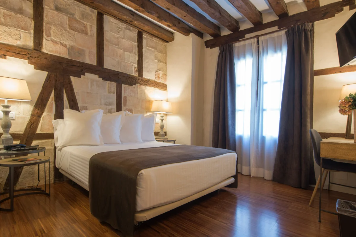 Habitación acogedora con cama doble, vigas de madera y luz cálida.
