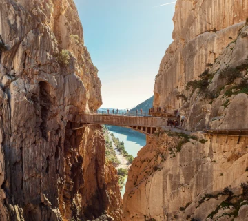 Puente colgante entre desfiladeros rocosos con fondo de cielo azul