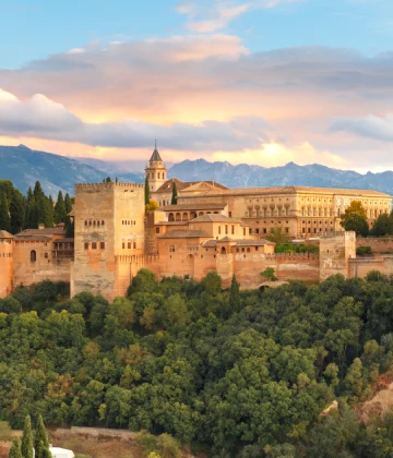 Vista del Palacio de la Aljafer&iacute;a al atardecer, con el r&iacute;o y monta&ntilde;as.