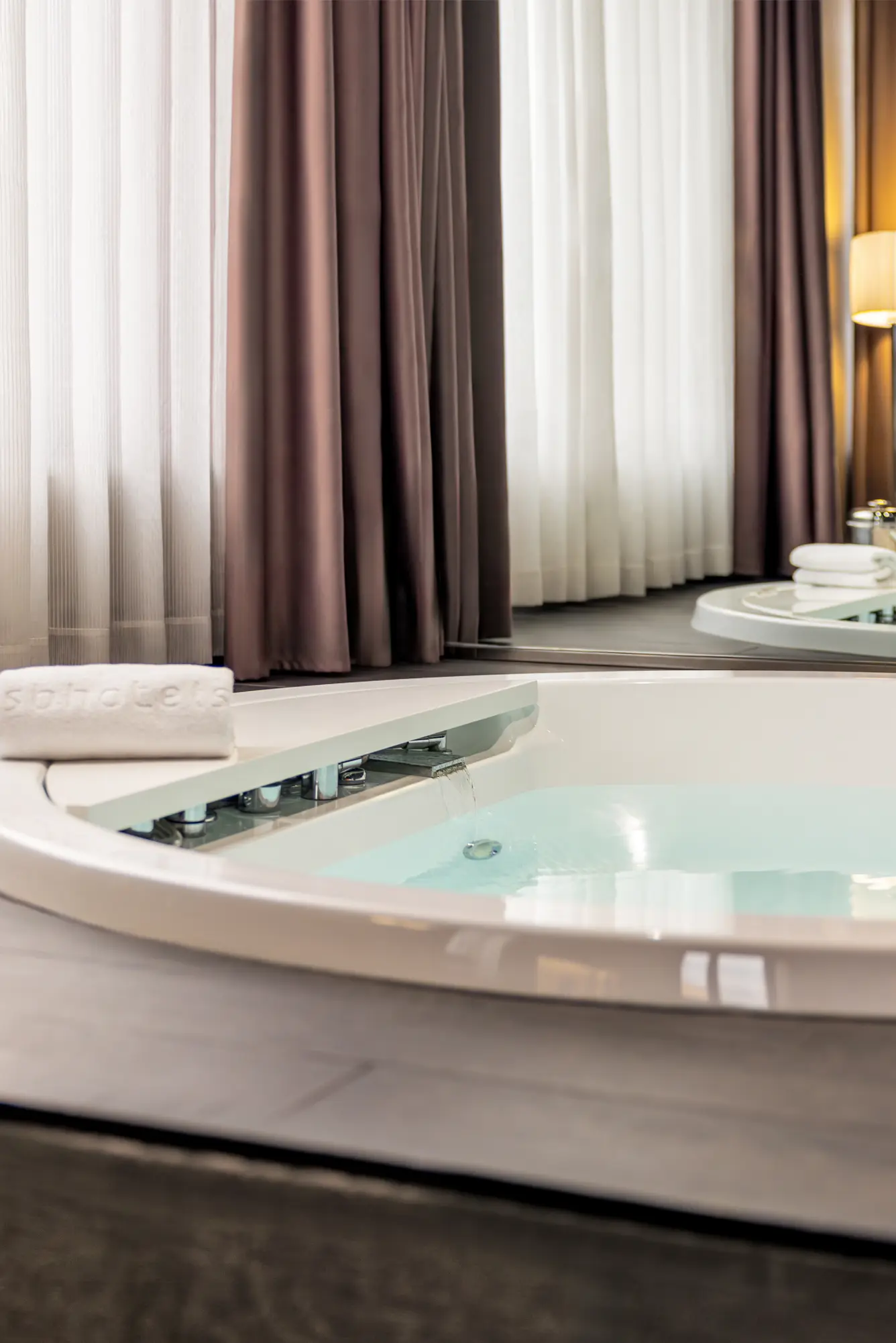 Stylish hotel bathroom showcasing a sleek jacuzzi and contemporary furnishings.