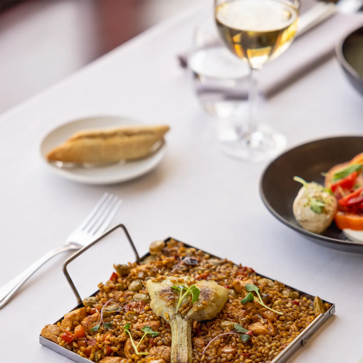 A delicious gourmet paella served on a stylish plate with a piece of artichoke.