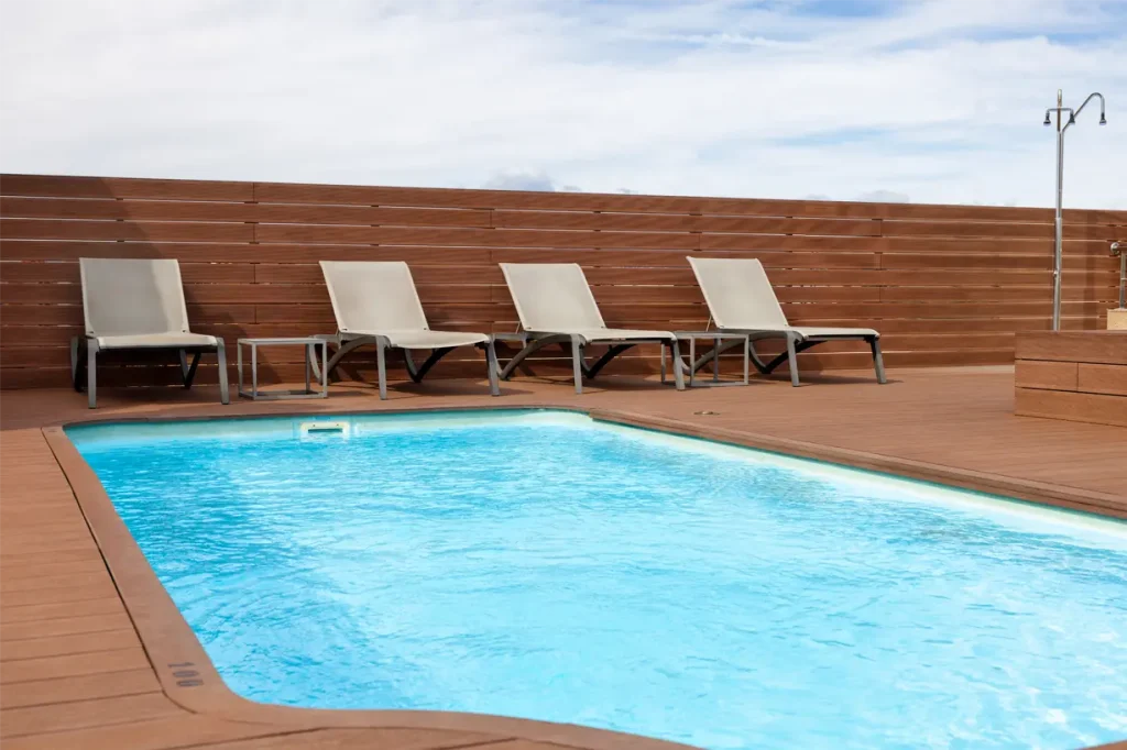 A modern poolside area with lounge chairs and a clear blue pool.