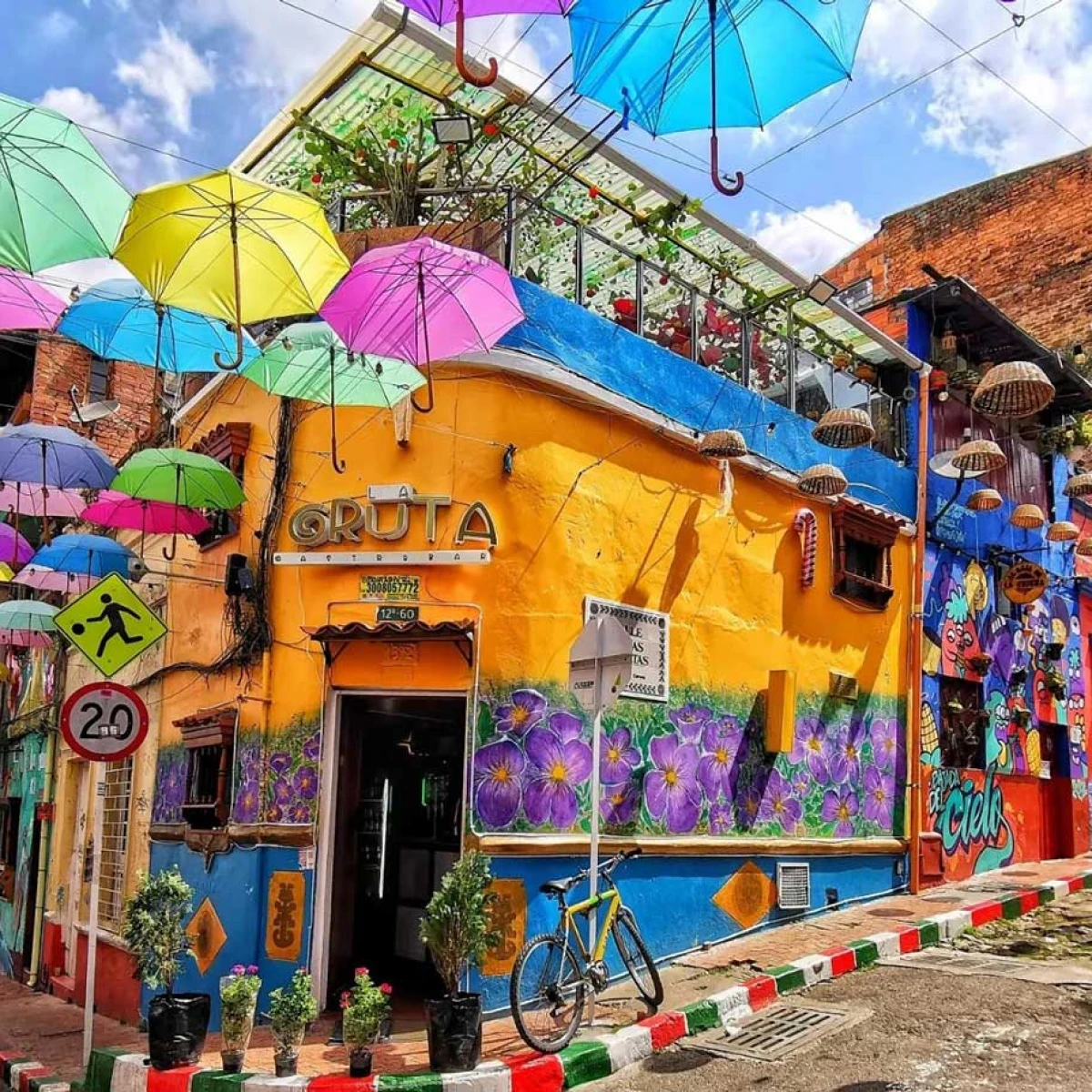 Calle colorida con paraguas, pared mural y letrero &ldquo;GRUTA&rdquo; en M&eacute;xico