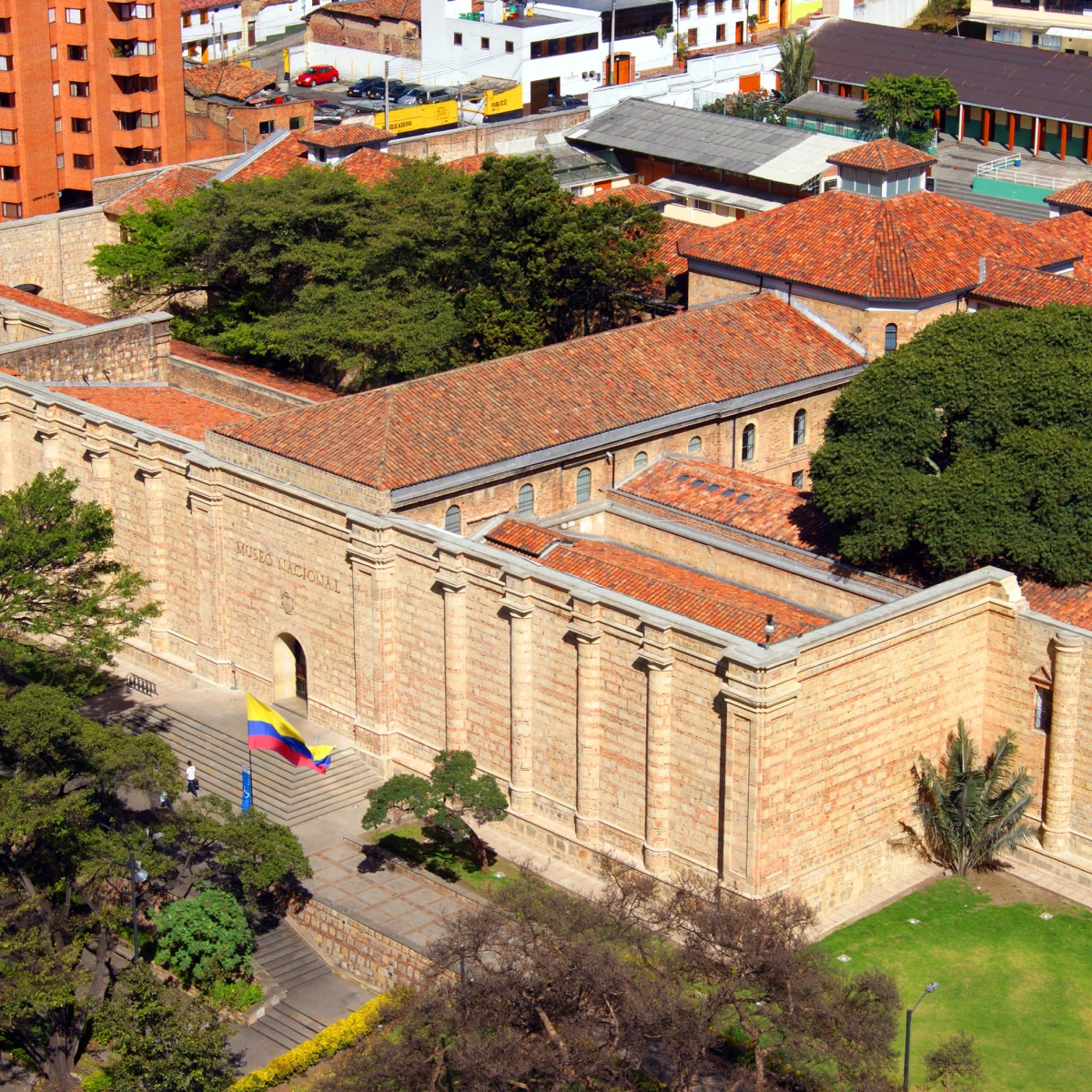 Edificio hist&oacute;rico de ladrillo con techo rojo, banderas y jardines en Colombia