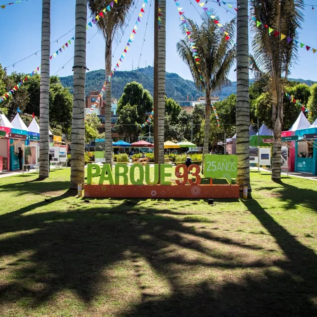 Entrada al evento &ldquo;Parque 93&rdquo; con palmeras, banderines y jardines al sol