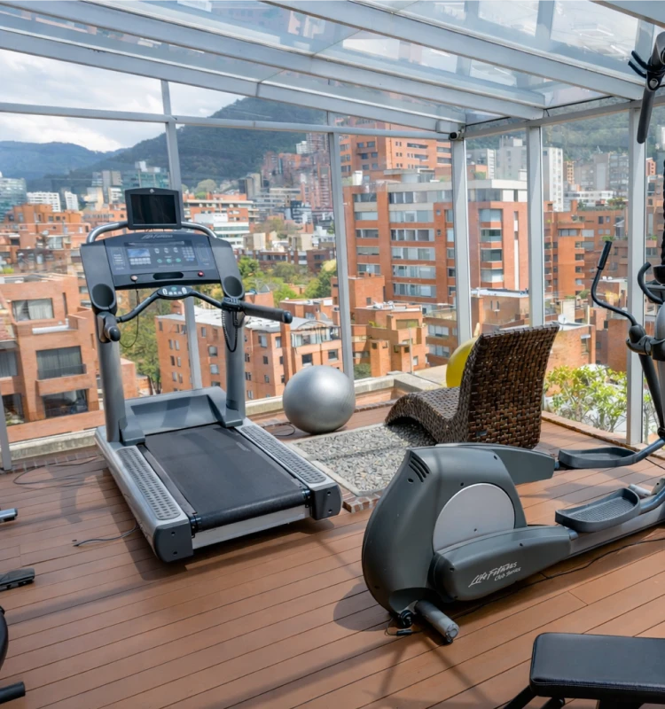 M&aacute;quinas de gimnasio en terraza con vista panor&aacute;mica a edificios y monta&ntilde;as