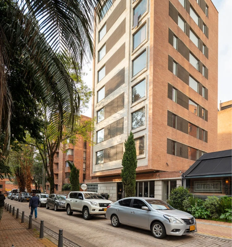 Edificio de oficinas con autos estacionados y palmeras al lado de la acera