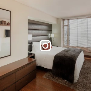 Dormitorio moderno con cama, sill&oacute;n y ventana con persianas