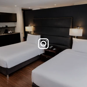 Habitaci&oacute;n de hotel con camas y cabecero oscuro, velas de l&aacute;mparas.