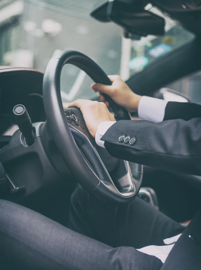 Persona conduciendo un coche, con manos en el volante y la caja de cambios