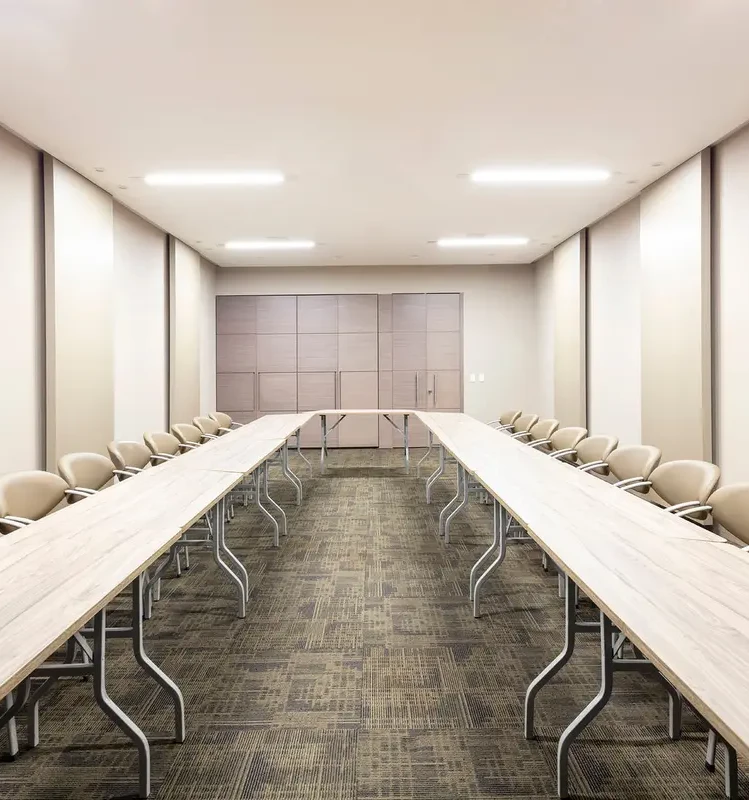 Sala de juntas moderna con mesas en forma de U y sillas beige