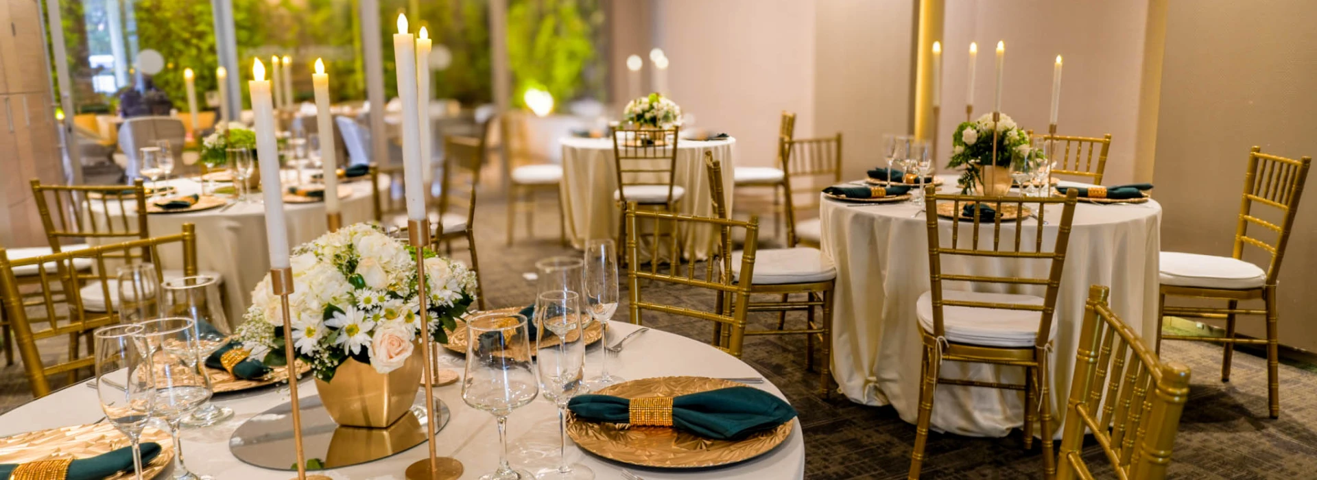 Mesa de banquete con velas, flores y sillas doradas en evento.