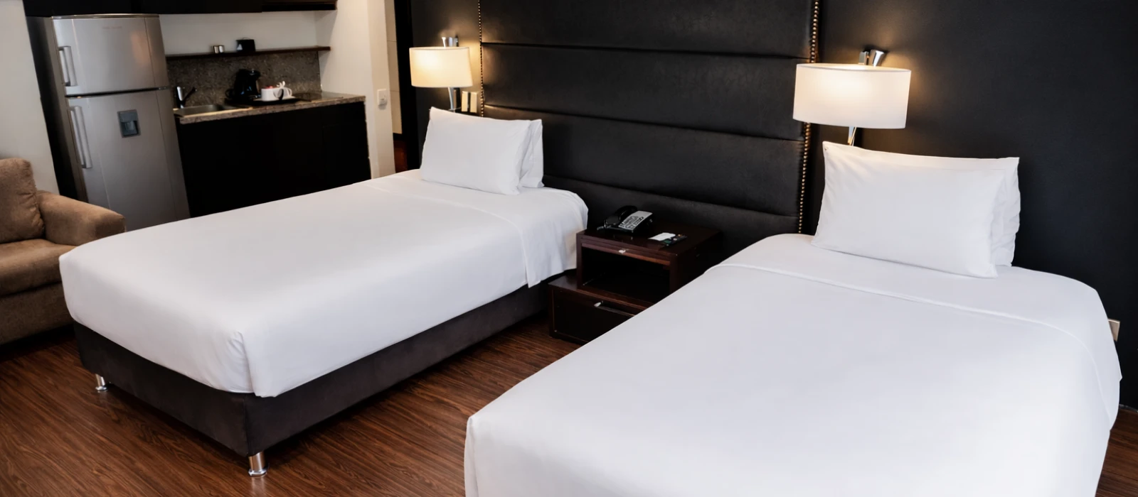 Habitaci&oacute;n de hotel con dos camas individuales y mesita con tel&eacute;fono