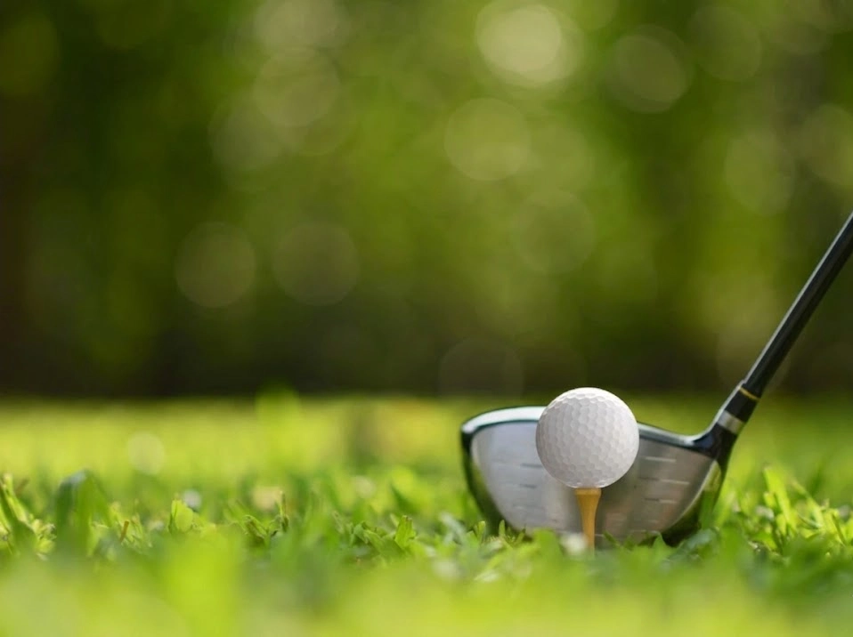 Bola de golfe em campo verde com tacos em fundo desfocado