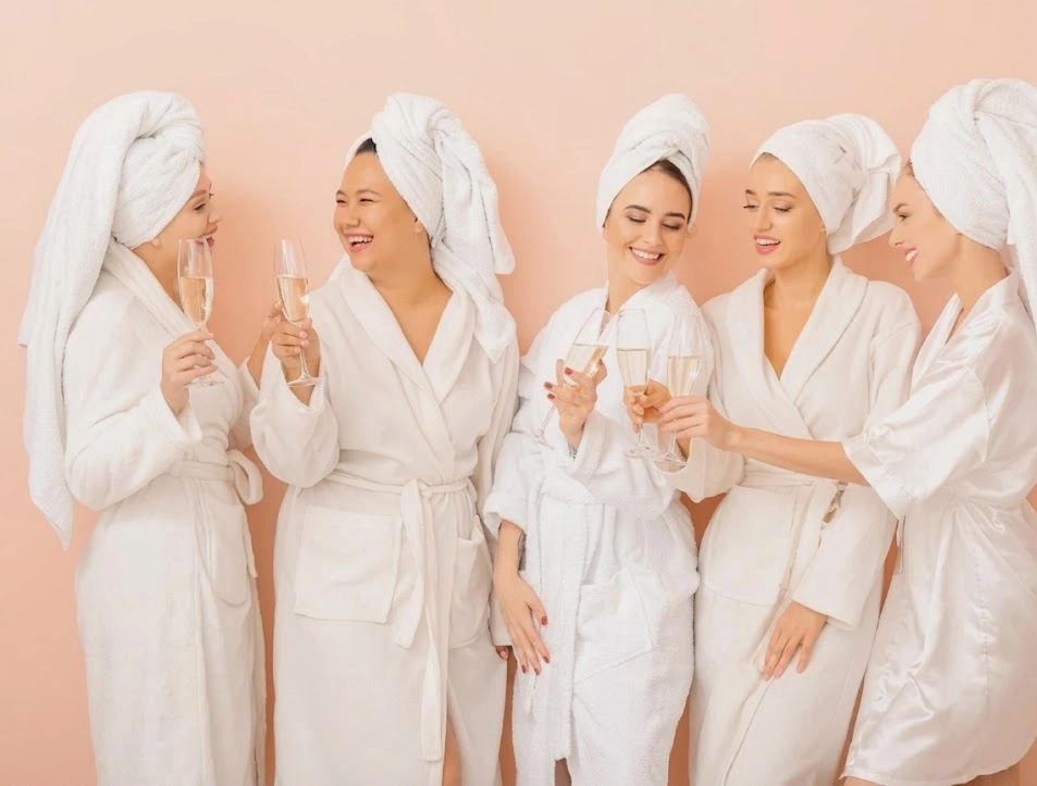 Mulheres de roup&atilde;o branco brindando com ta&ccedil;as de champanhe em grupo