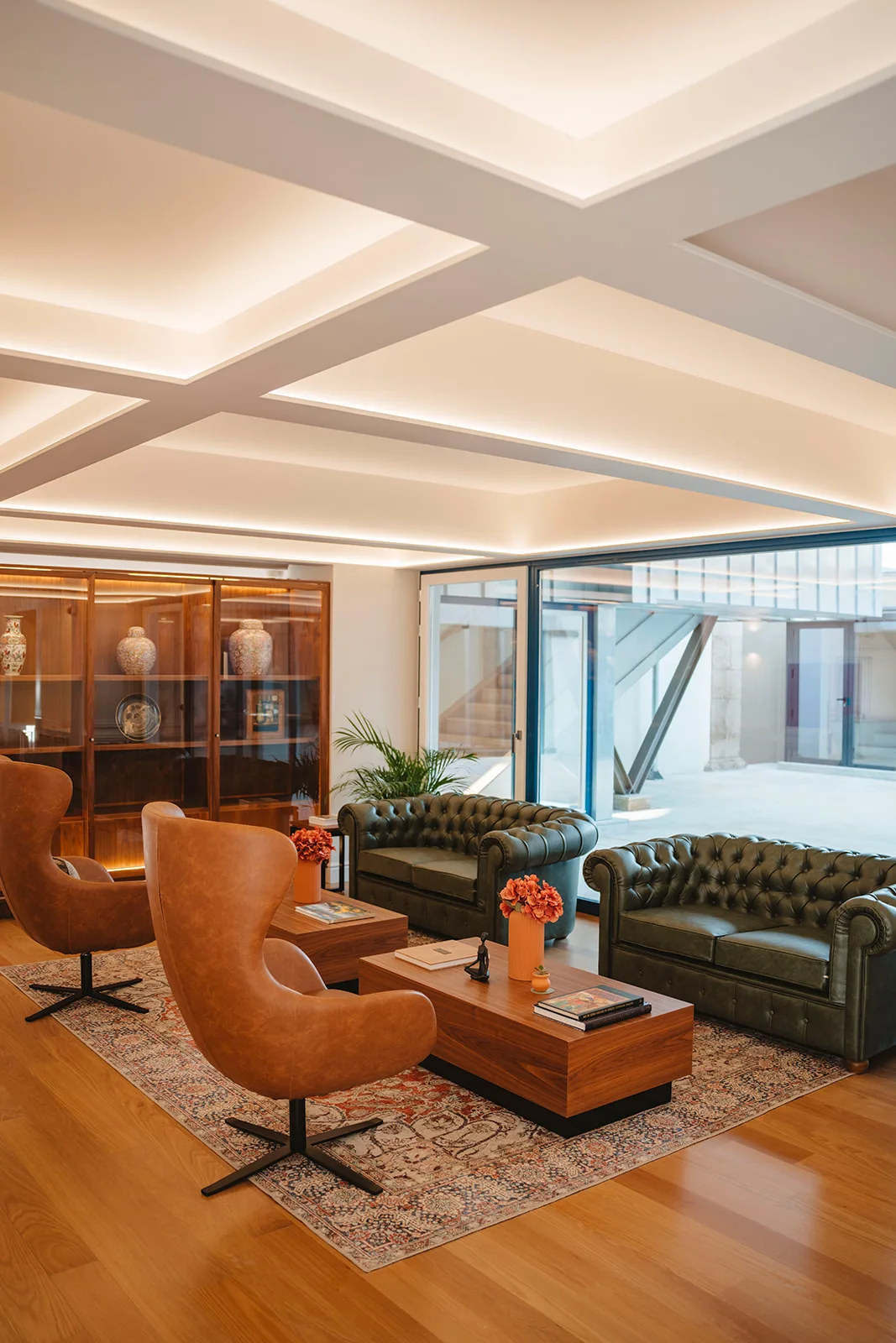 Sala de estar com sof&aacute;s verdes, poltronas e mesa de madeira.
