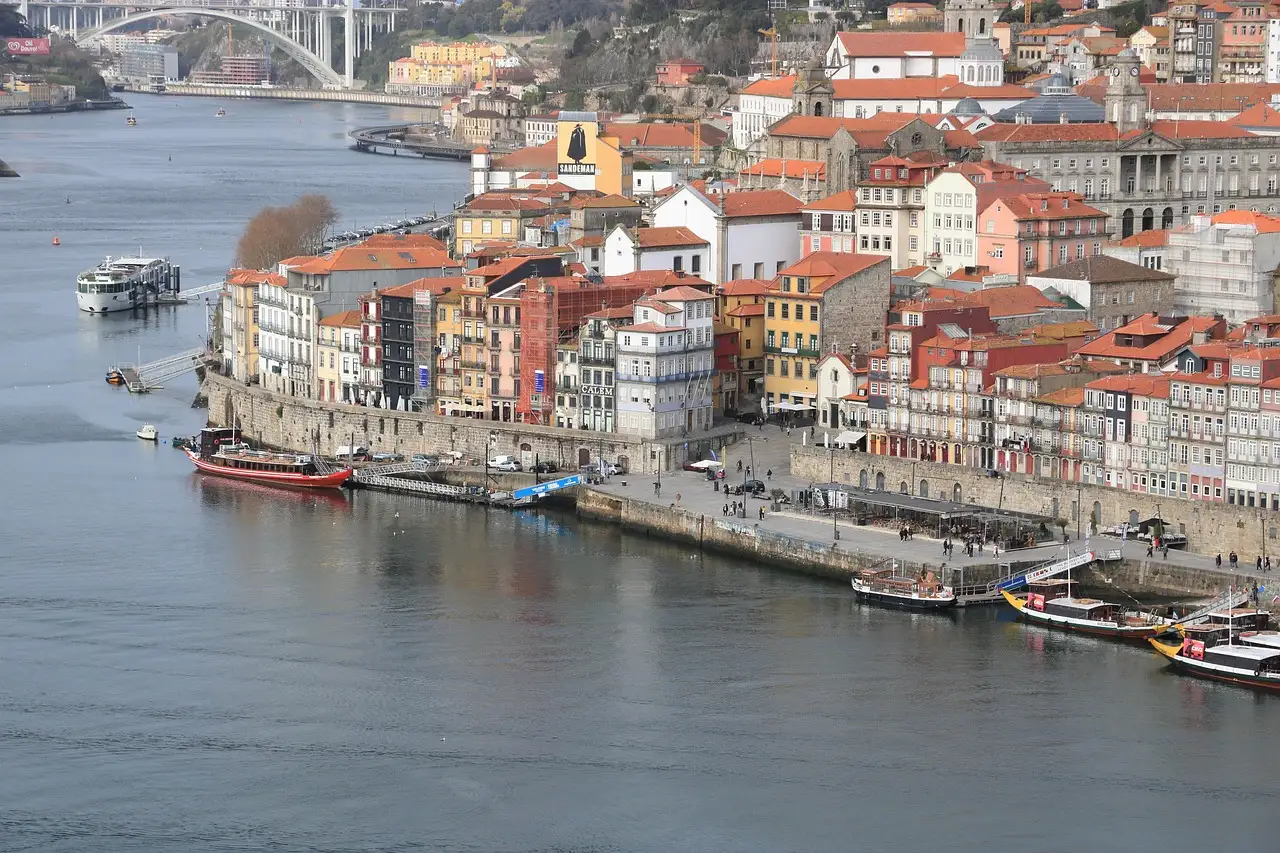 Ribeira colorida com pr&eacute;dios e barcos no rio Douro.