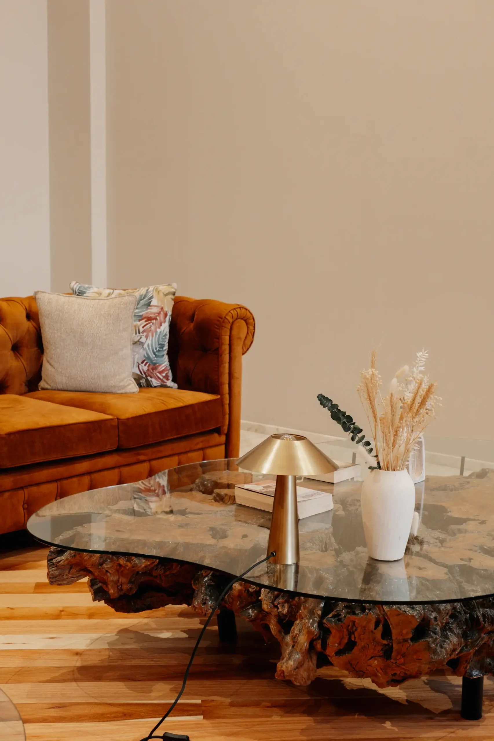 Sala com sof&aacute; laranja, mesa de centro r&uacute;stica e lumin&aacute;ria dourada.