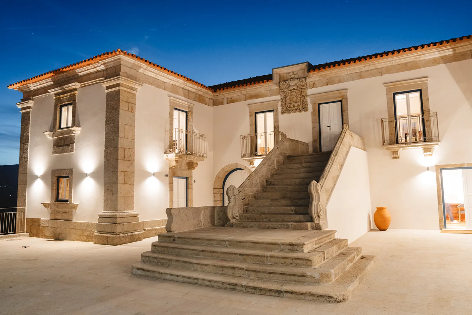 Mans&atilde;o hist&oacute;rica iluminada &agrave; noite com escadaria e cer&acirc;mica.