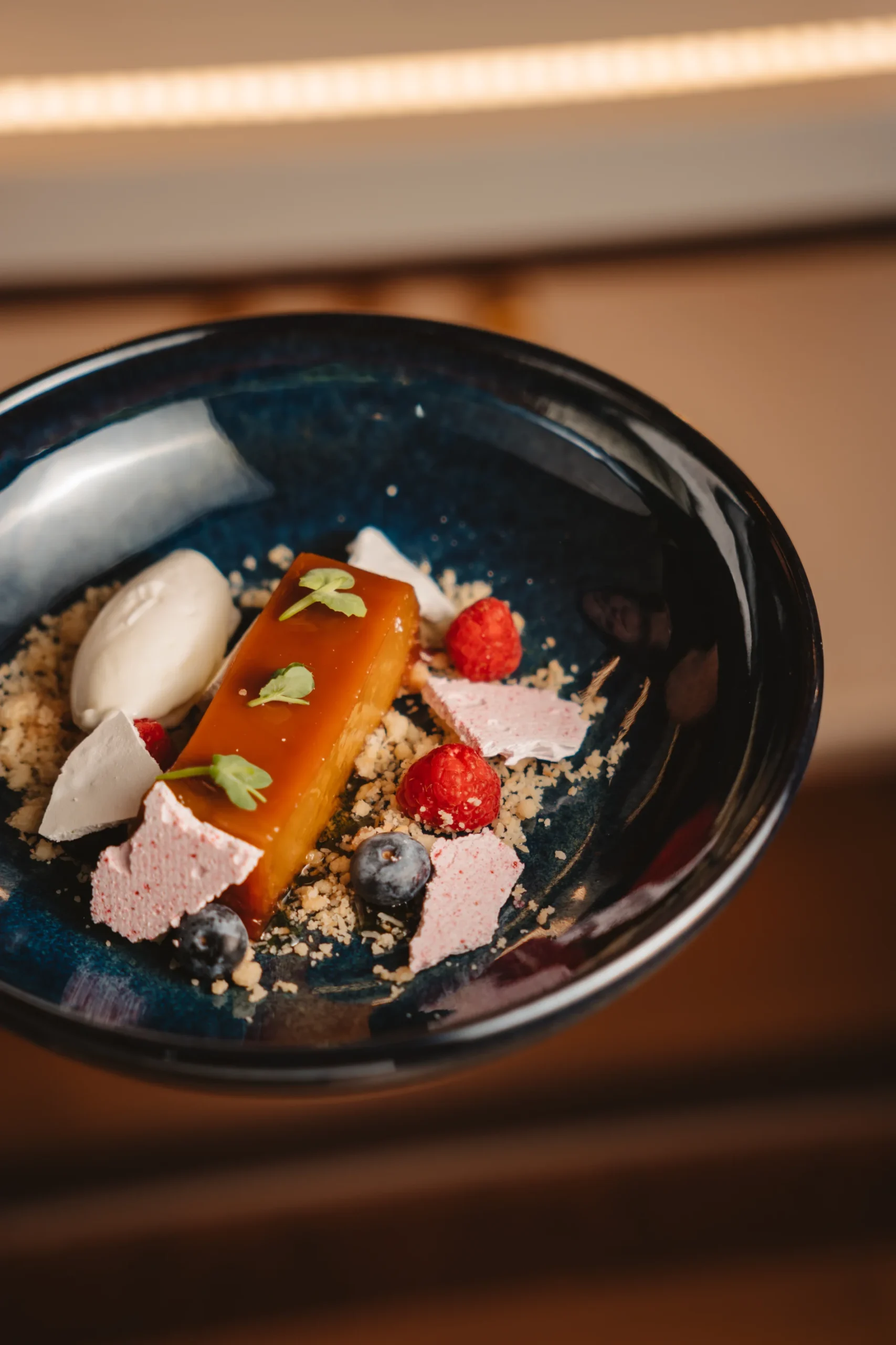 Sobremesa gourmet com frutas e creme em prato azul.