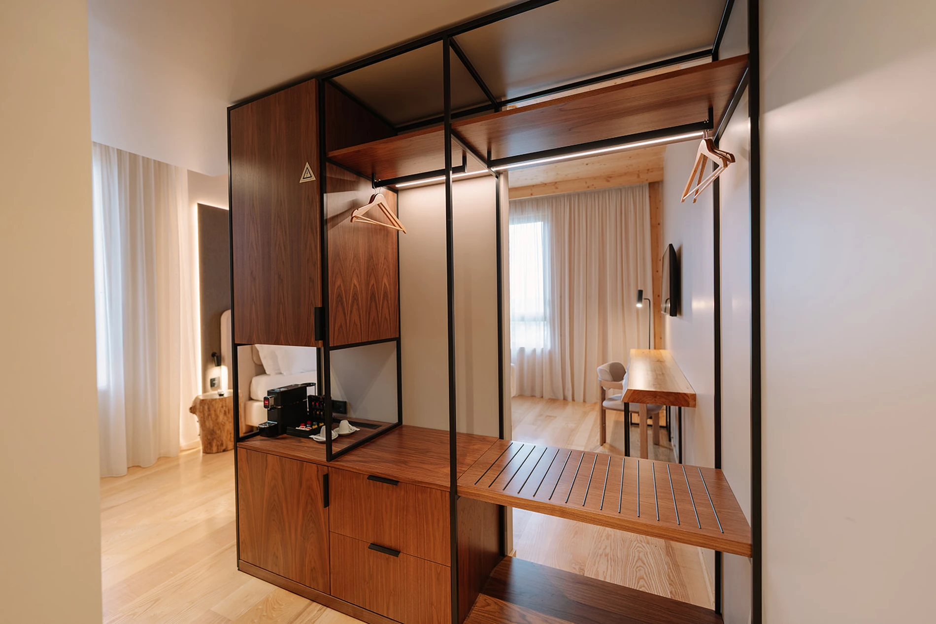 Quarto de hotel moderno com mob&iacute;lia de madeira e janelas grandes.