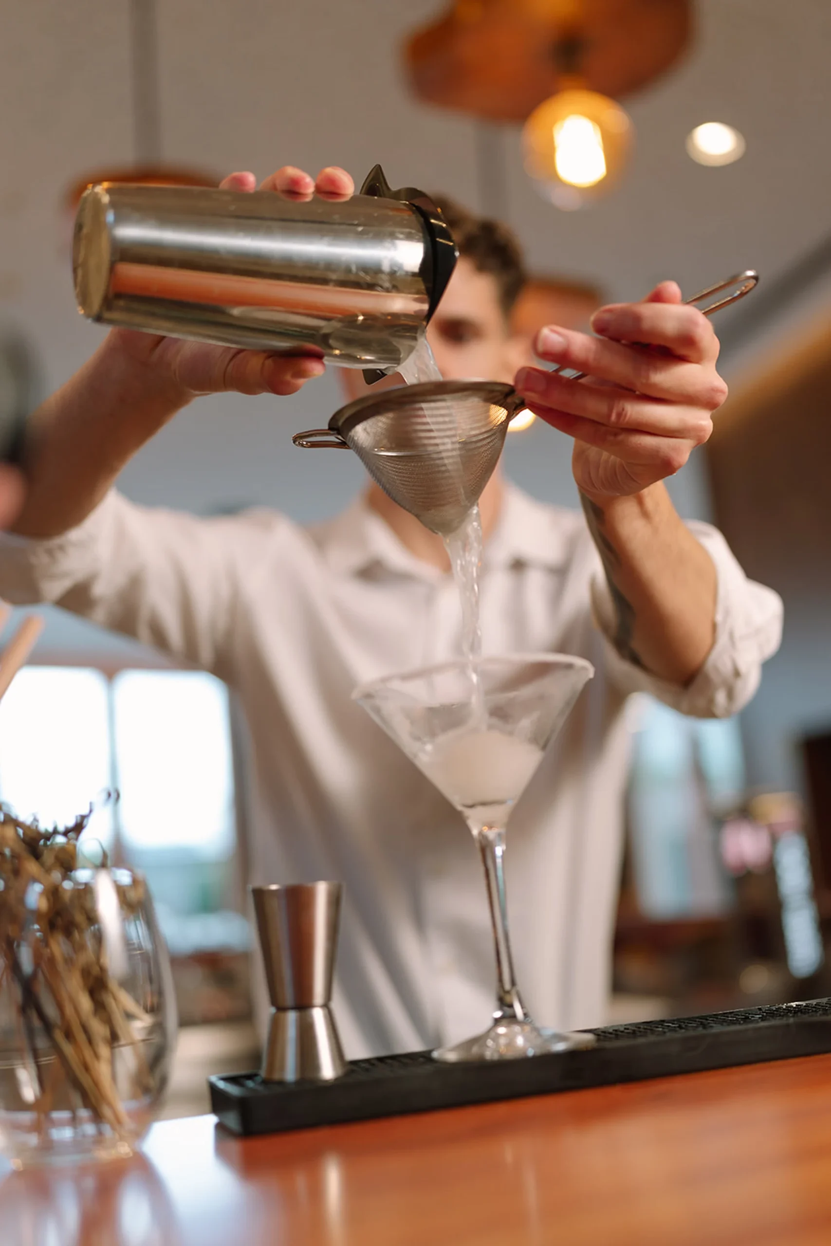 Bartender coando coquetel em ta&ccedil;a de Martini.