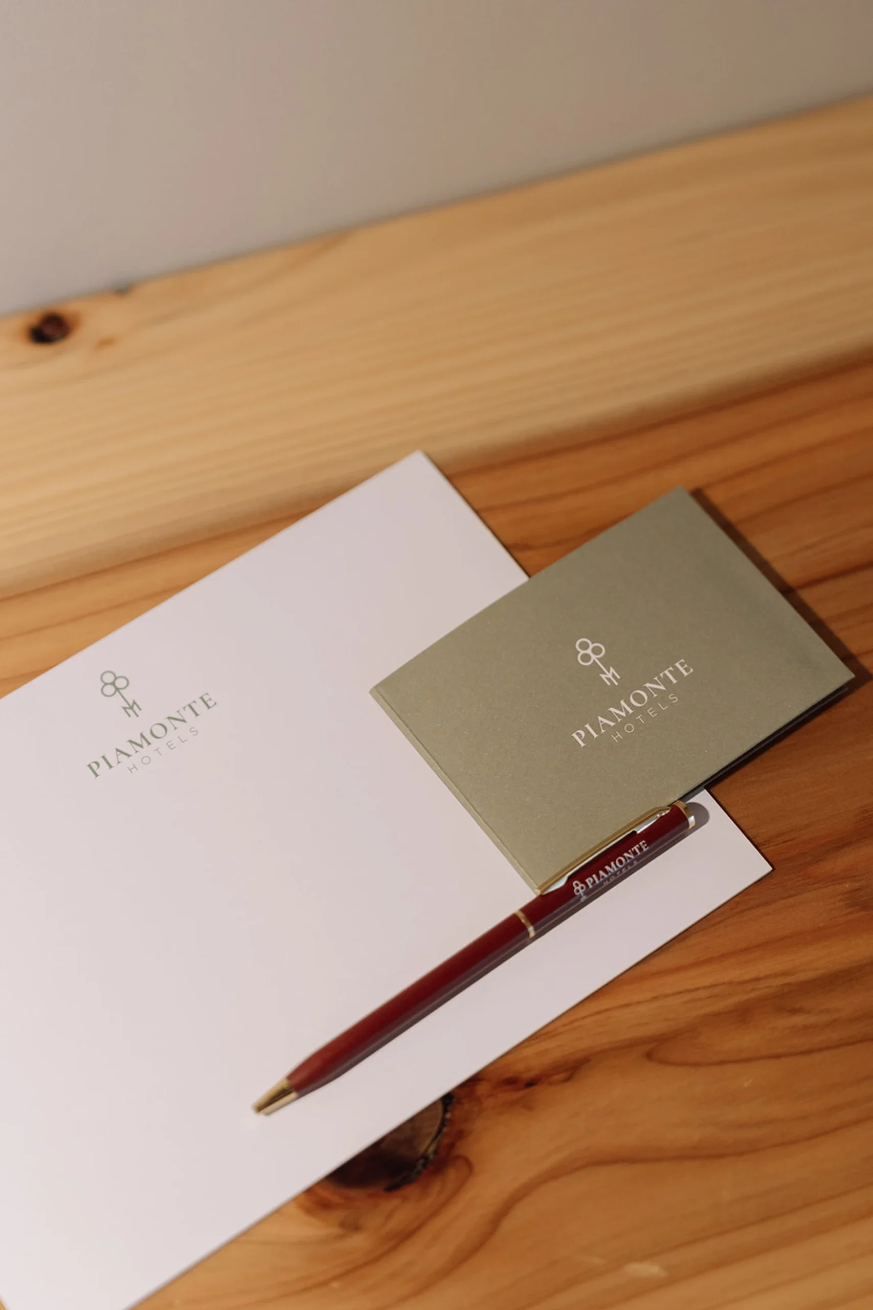 Papel e envelope do Piamonte Hotels sobre a mesa, com uma caneta vermelha.